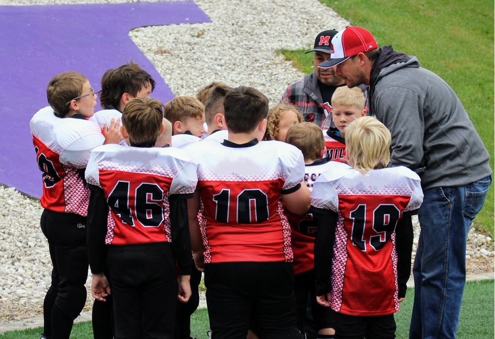 Coach talking to young football players